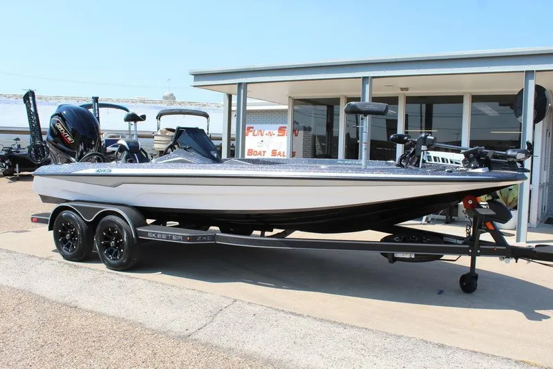 Slide: The Image of 2026 Skeeter ZXE21 boat with powerful outboard motor, parked near a modern building. - 2