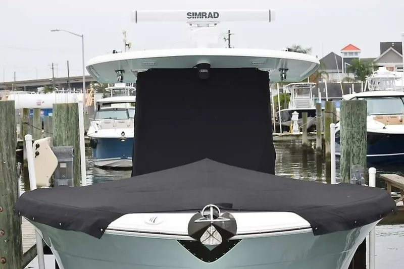 Slide: The Image of 2018 Robalo R302 Center Console boat docked with black cover, marina background. - 12