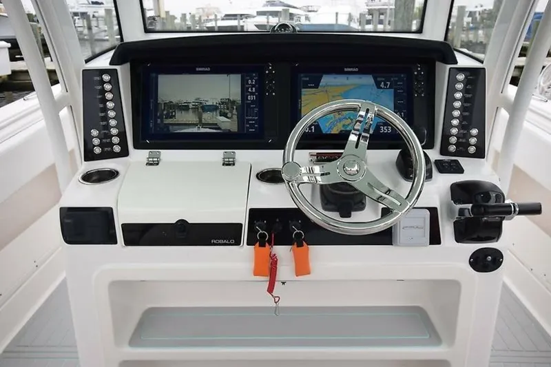 Slide: The Image of 2018 Robalo R302 Center Console boat dashboard with dual displays and steering wheel. - 18