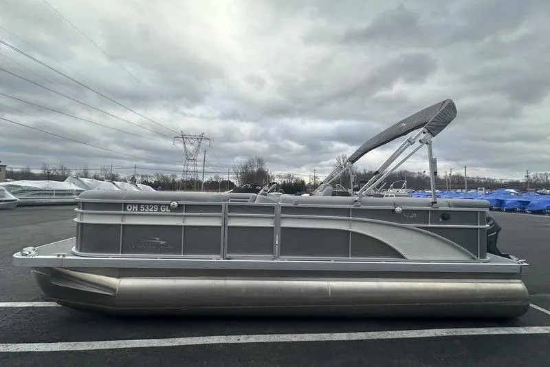 Slide: The Image of 2023 Bennington 21 SL pontoon boat parked under cloudy skies. - 3