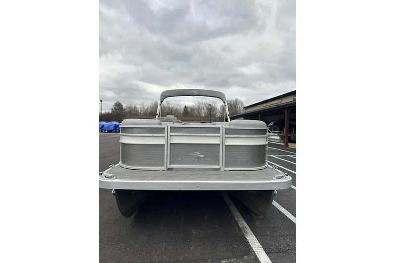 Slide: The Image of 2023 Bennington 21 SL pontoon boat parked outdoors under cloudy skies. - 6