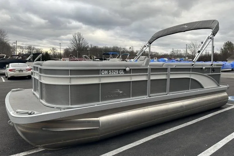Slide: The Image of 2023 Bennington 21 SL pontoon boat parked in a lot under cloudy skies. - 7