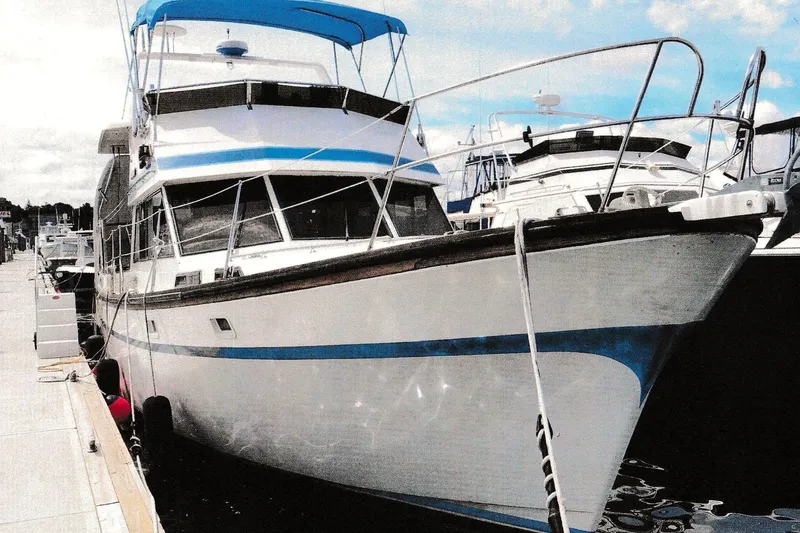 Slide: The Image of 1984 President D/C Motoryacht/Trawler docked at marina, featuring blue accents and spacious deck. - 0