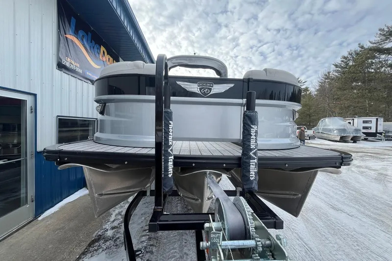Slide: The Image of 2018 Avalon Excalibur Elite Windshield boat on trailer, parked outside dealership. - 6
