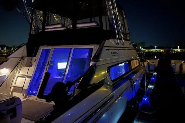 Slide: The Image of 1999 Carver 380 Santego yacht illuminated at night with blue interior lights. - 18