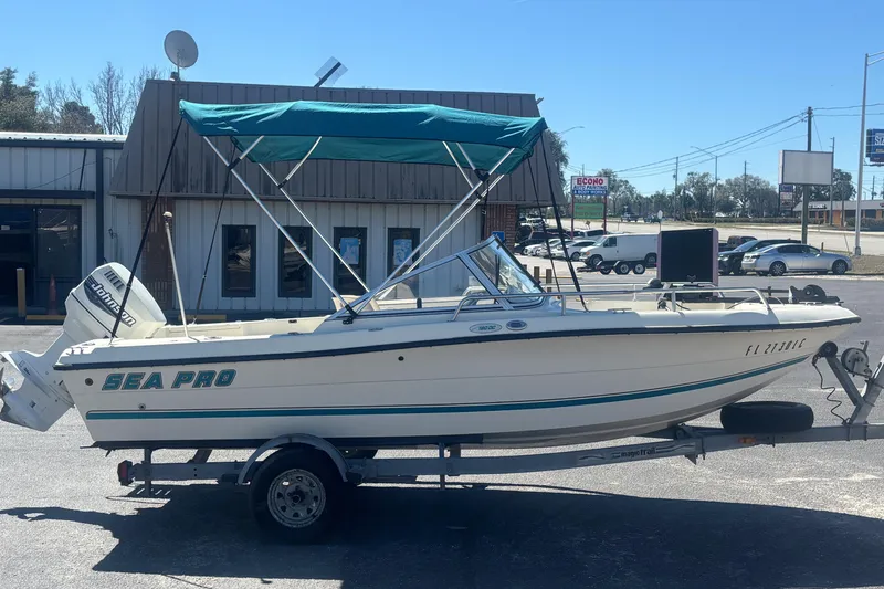 Slide: The Image of 2000 Sea Pro 180 Dual Console boat with canopy on trailer, parked outside a building. - 5