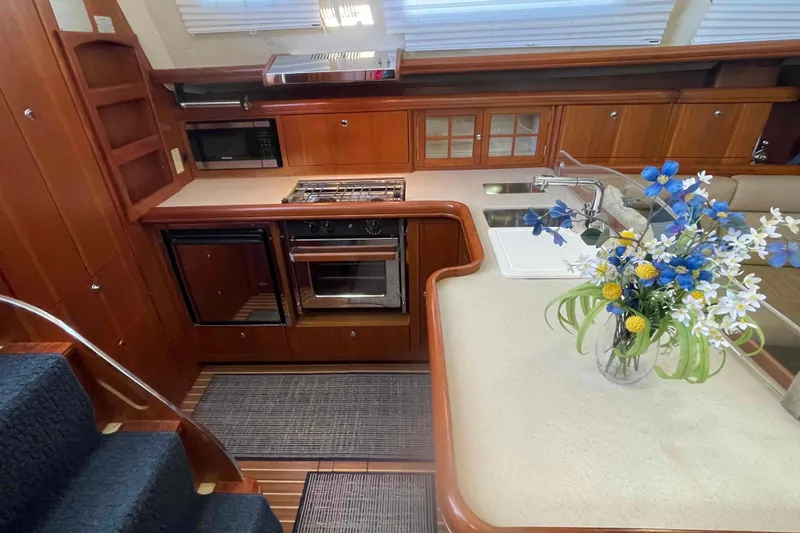 Slide: The Image of Luxurious 2003 Hunter 426 Deck Salon kitchen with wood cabinetry and floral centerpiece. - 21