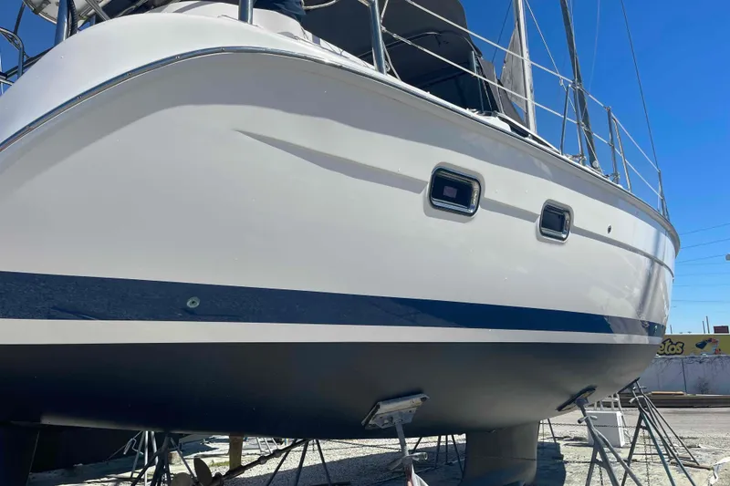 Slide: The Image of 2003 Hunter 426 Deck Salon sailboat on dry dock, side view under clear blue sky. - 75