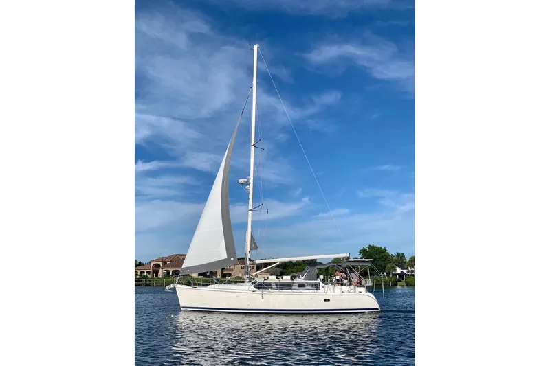Slide: The Image of 2003 Hunter 426 Deck Salon sailboat on calm water under blue sky. - 88