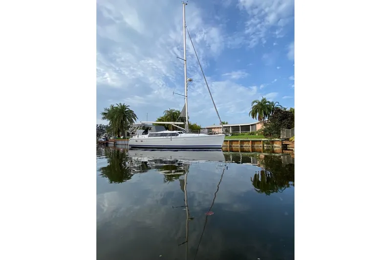 Slide: The Image of Sailboat Hunter 426 Deck Salon 2003 docked on calm water with palm trees in background. - 92