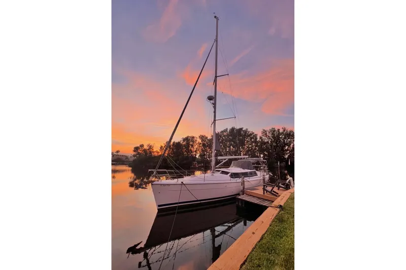 Slide: The Image of 2003 Hunter 426 Deck Salon sailboat docked at sunset, reflecting on calm water. - 94