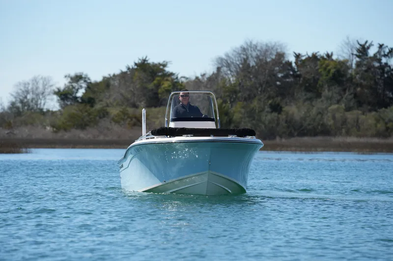Slide: The Image of 2025 Grady-White Fisherman 180 boat cruising on calm water near a wooded shoreline. - 7