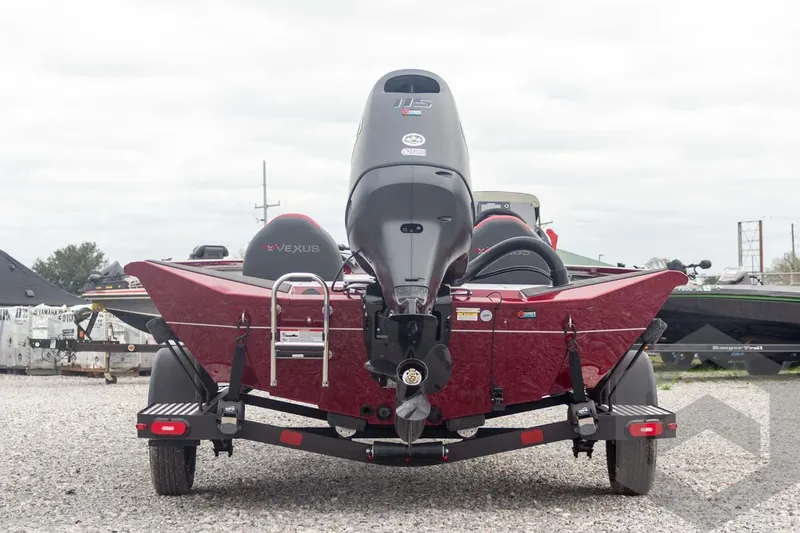 Slide: The Image of 2026 Vexus Defender 189 boat, rear view, on a gravel lot with overcast sky. - 10