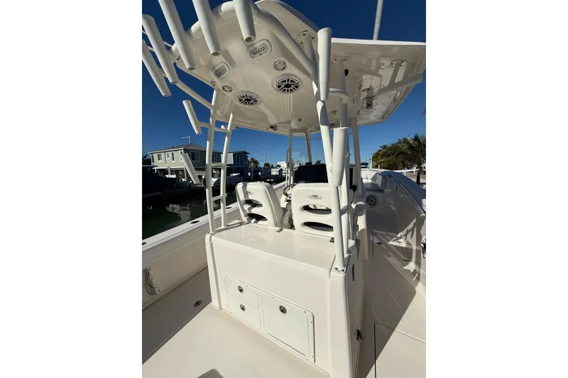 Slide: The Image of 2022 Cobia 320 Center Console boat with rod holders and seating, docked under clear sky. - 10