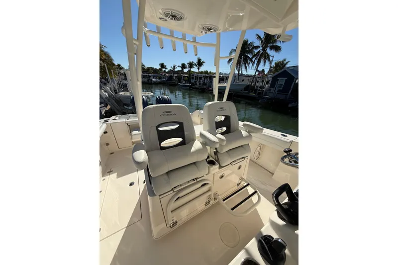 Slide: The Image of 2022 Cobia 320 Center Console boat interior with dual seats, docked near palm trees. - 20
