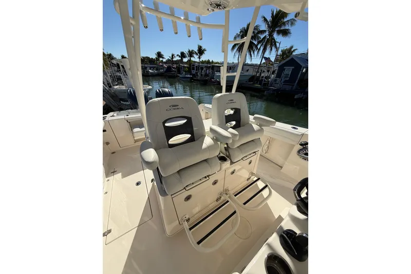 Slide: The Image of 2022 Cobia 320 Center Console boat interior with dual seats and palm trees in the background. - 21
