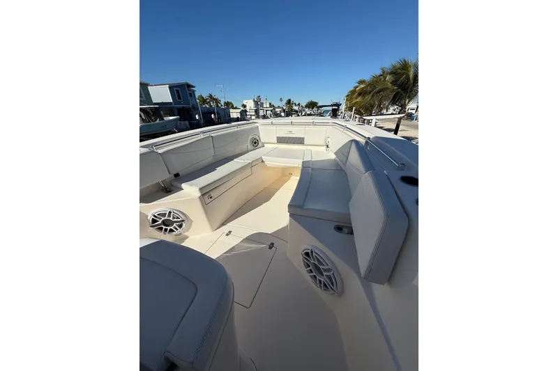 Slide: The Image of 2022 Cobia 320 Center Console boat interior with seating and speakers, docked under clear blue sky. - 24