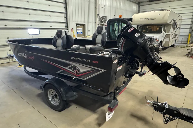 Slide: The Image of 2020 Alumacraft Competitor 165 Tiller boat in garage with Suzuki outboard motor. - 4