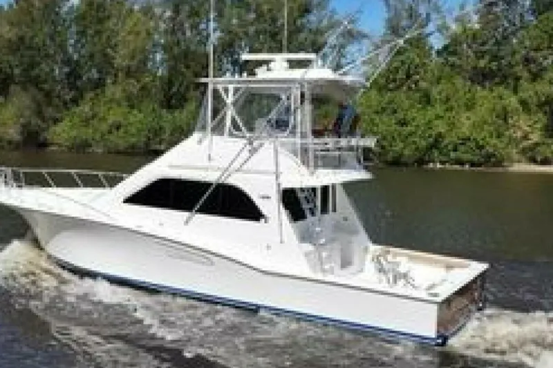 Slide: The Image of 2004 Cabo 48 Flybridge yacht cruising on a river with lush greenery. - 10