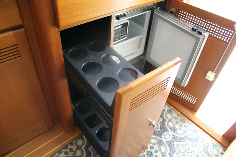 Slide: The Image of 2004 Cabo 48 Flybridge interior with open wooden cabinet and built-in refrigerator. - 15