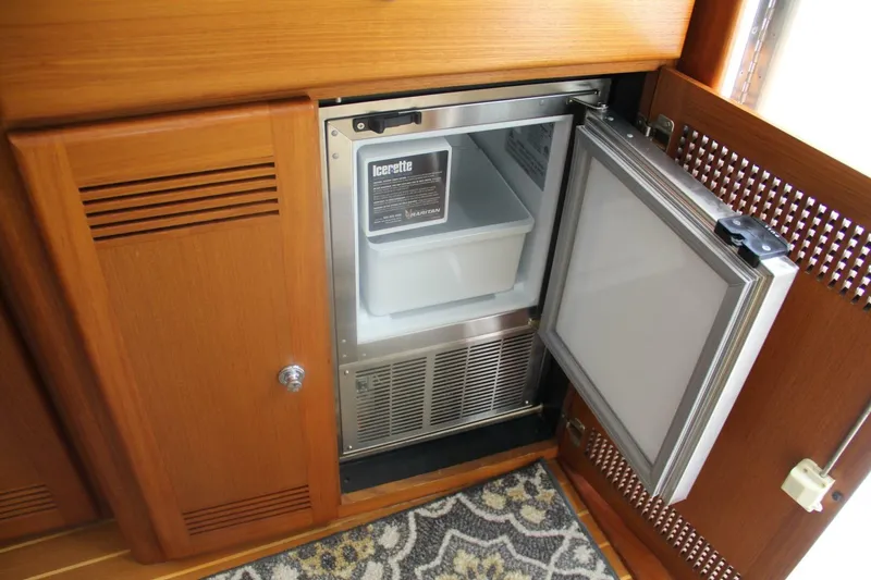 Slide: The Image of Open ice maker in 2004 Cabo 48 Flybridge yacht's wooden cabinet interior. - 16