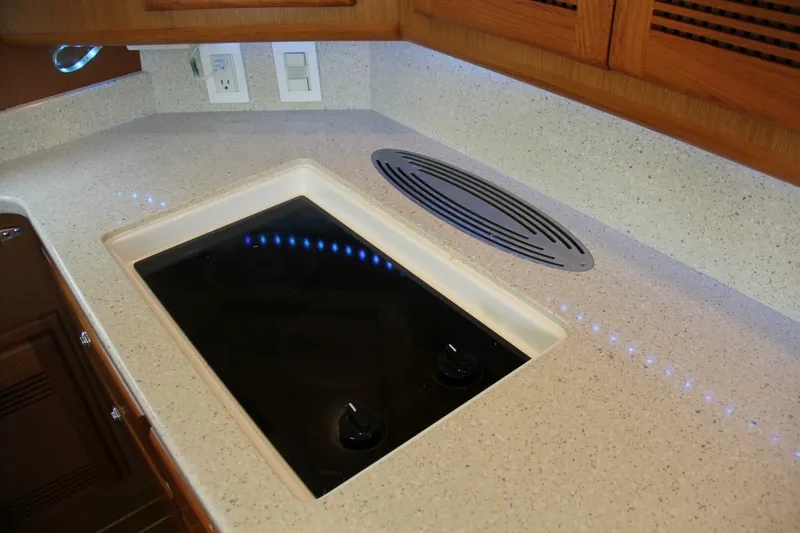 Slide: The Image of 2004 Cabo 48 Flybridge kitchen with sleek countertop and modern stovetop. - 18