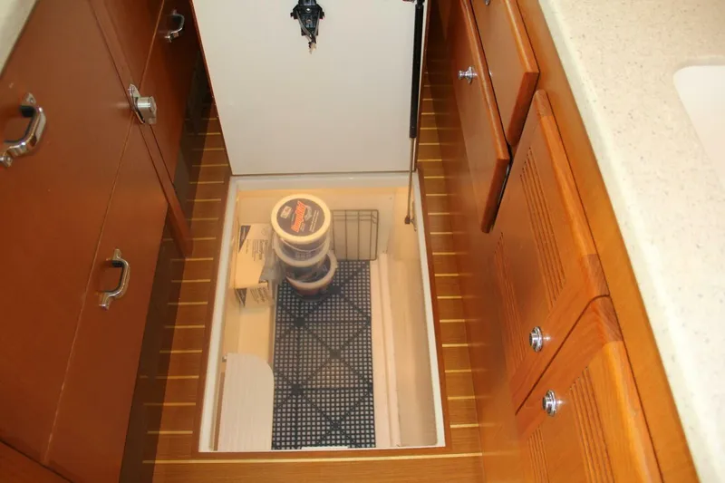 Slide: The Image of 2004 Cabo 48 Flybridge yacht interior storage compartment with wooden cabinetry and organized supplies. - 21