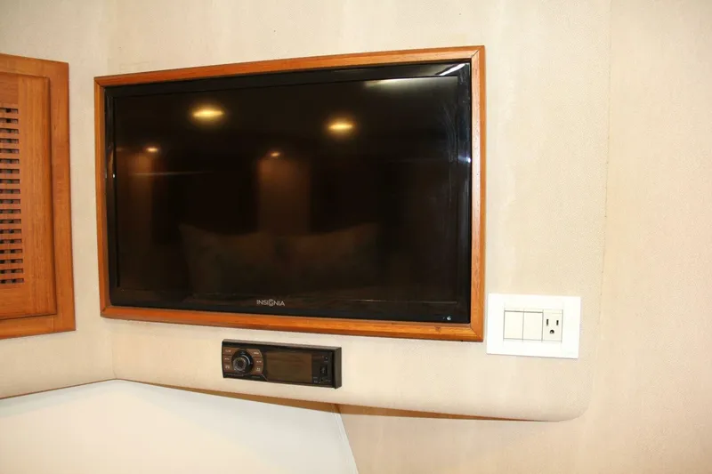 Slide: The Image of Flat-screen TV and control panel in 2004 Cabo 48 Flybridge interior. - 24