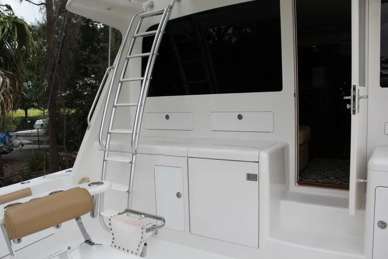 Slide: The Image of 2004 Cabo 48 Flybridge yacht with ladder and open cabin door. - 3