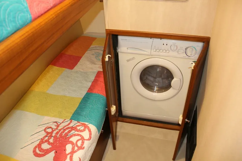Slide: The Image of Laundry area in 2004 Cabo 48 Flybridge with colorful bedding and washing machine. - 30