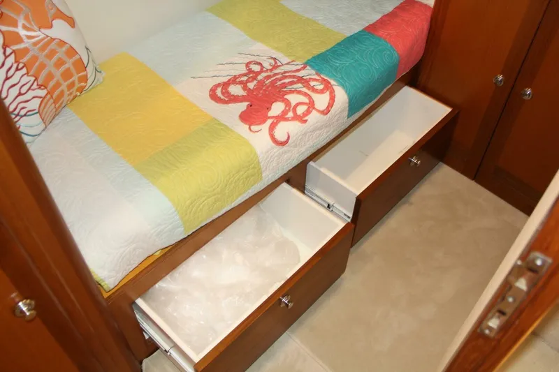 Slide: The Image of 2004 Cabo 48 Flybridge cabin with colorful bedding and open storage drawers. - 31