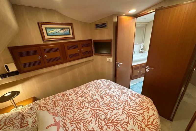 Slide: The Image of 2004 Cabo 48 Flybridge cabin with cozy bed, wooden cabinets, and ensuite bathroom. - 37