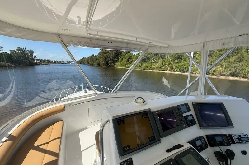 Slide: The Image of 2004 Cabo 48 Flybridge helm with navigation screens, cruising on a serene river. - 43
