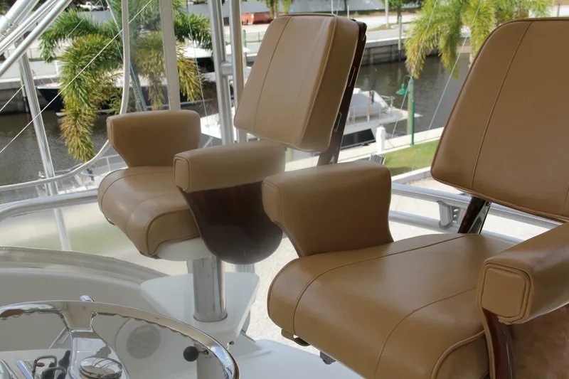Slide: The Image of Luxurious leather seats on a 2004 Cabo 48 Flybridge yacht, overlooking a marina. - 45