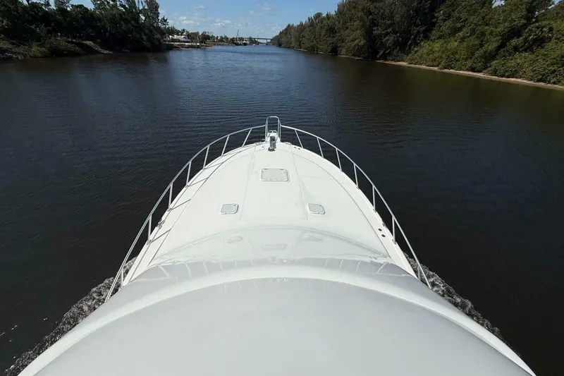 Slide: The Image of Bow view of 2004 Cabo 48 Flybridge yacht cruising on a calm river. - 59