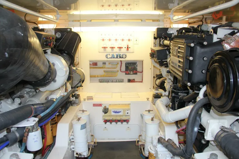Slide: The Image of Engine room of 2004 Cabo 48 Flybridge yacht, showcasing dual engines and control systems. - 62