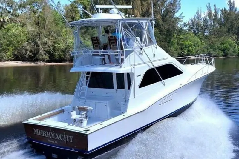 Slide: The Image of 2004 Cabo 48 Flybridge yacht cruising on a serene river, surrounded by lush greenery. - 70