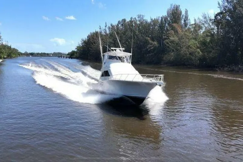 Slide: The Image of 2004 Cabo 48 Flybridge cruising on a scenic river under a clear blue sky. - 9