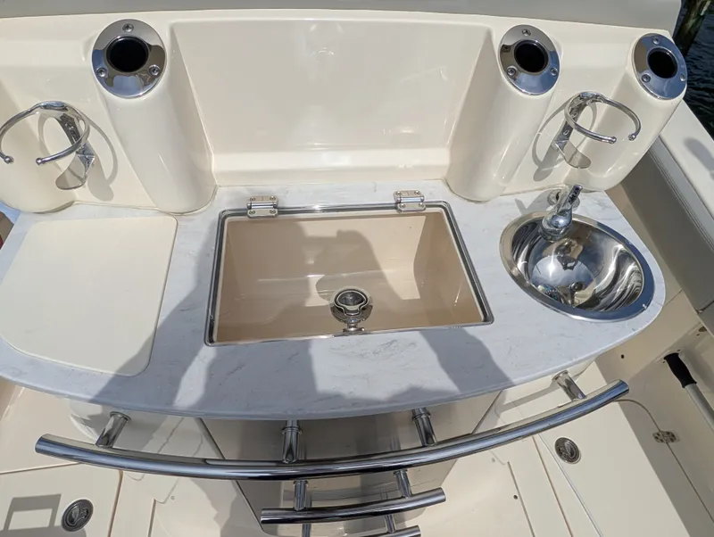 Slide: The Image of 2024 Scout 277 LXF boat kitchenette with sink and fishing rod holders. - 43