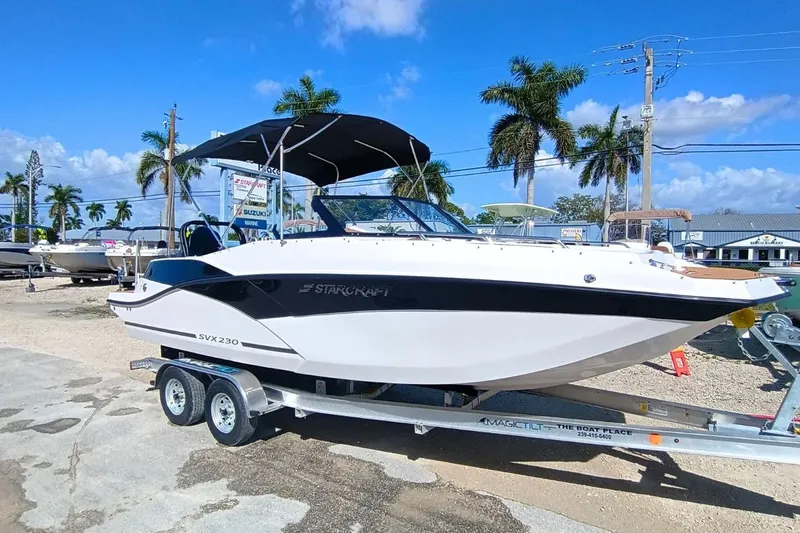 The Image of 2026 Starcraft SVX 230 DC OB boat on trailer, sunny day, palm trees in background. - 0