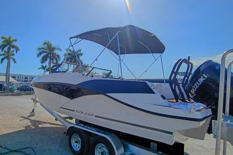 Slide: The Image of 2026 Starcraft SVX 230 DC OB boat on trailer, sunny day, palm trees in background. - 6