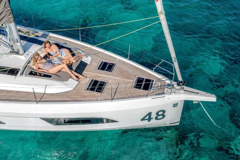 Slide: The Image of 2026 Dufour 48 yacht with two people relaxing on deck, surrounded by clear turquoise water. - 5