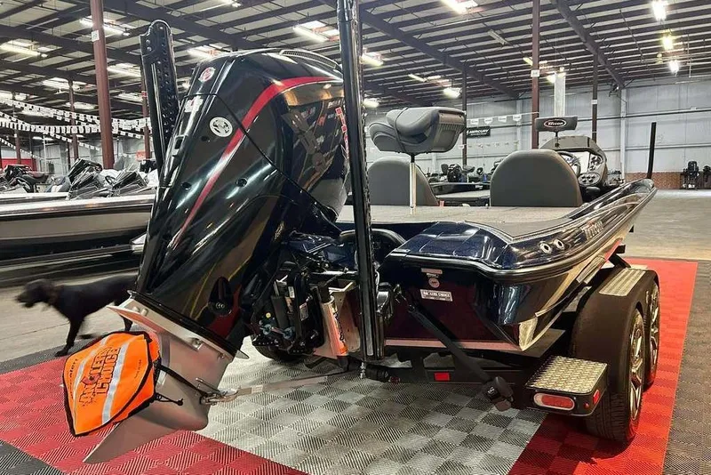 Slide: The Image of 2023 Triton 20 TrX Patriot boat in showroom, featuring powerful outboard motor. - 10