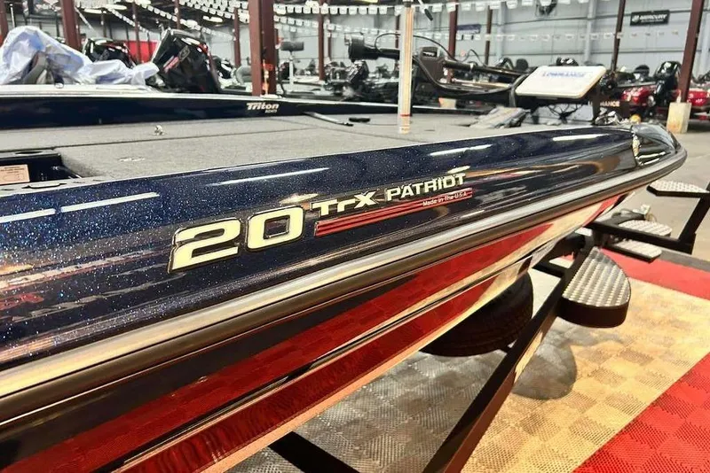 Slide: The Image of 2023 Triton 20 TrX Patriot boat displayed in showroom, showcasing sleek design and branding. - 11