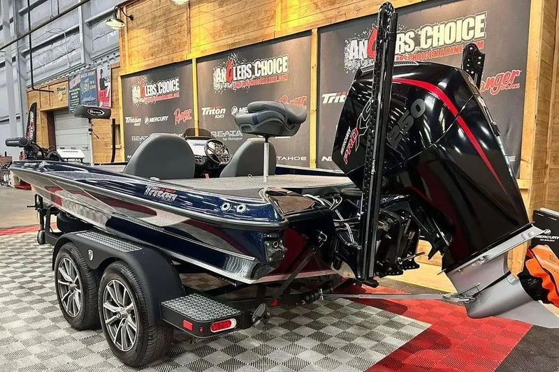 Slide: The Image of 2023 Triton 20 TrX Patriot bass boat displayed indoors with powerful engine. - 3