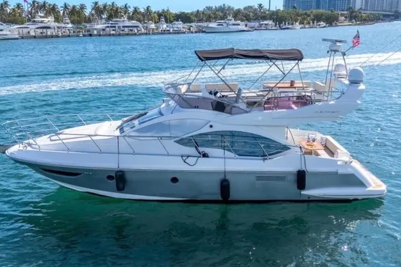 Slide: The Image of 2013 Azimut 45 yacht cruising on clear blue water near a marina. - 2