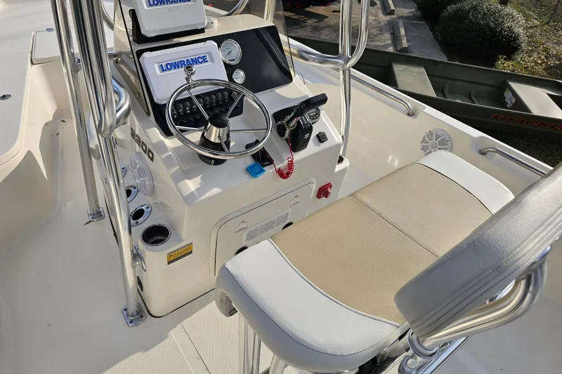 Slide: The Image of 2024 Bulls Bay 2200 boat cockpit with steering wheel, Lowrance electronics, and cushioned seating. - 13
