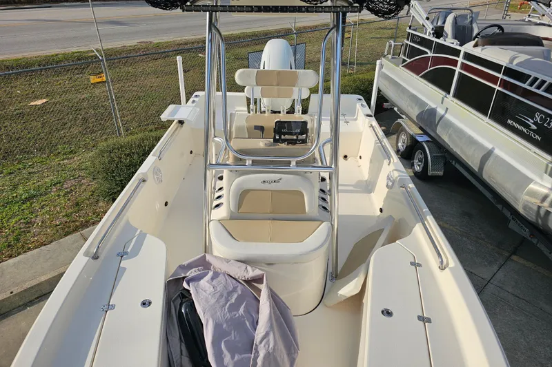 Slide: The Image of 2024 Bulls Bay 2200 boat interior with seating and console, parked near a fence. - 7