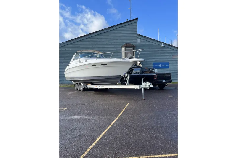 The Image of 1996 Sea Ray Sundancer 330 on trailer, parked outside a blue building. - 1