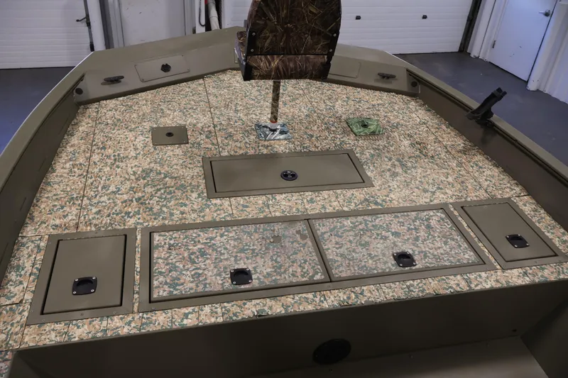 Slide: The Image of 2022 Tracker Grizzly 2072 MVX CC boat interior with camo flooring and storage compartments. - 13